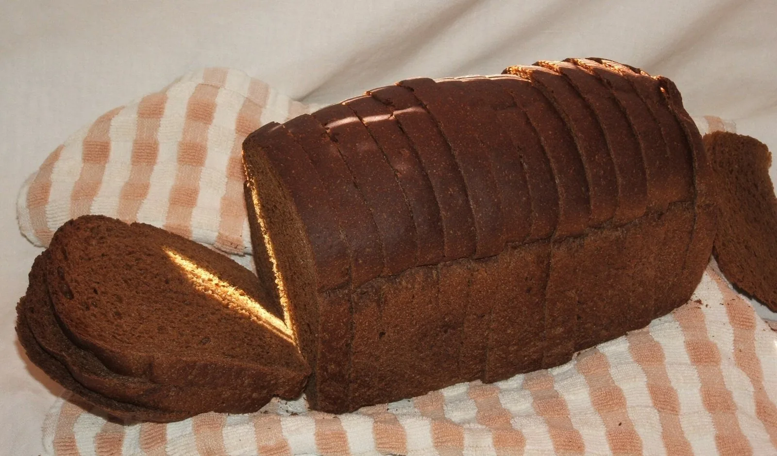 Pagnotta di pane scuro di segale affettata su un canovaccio